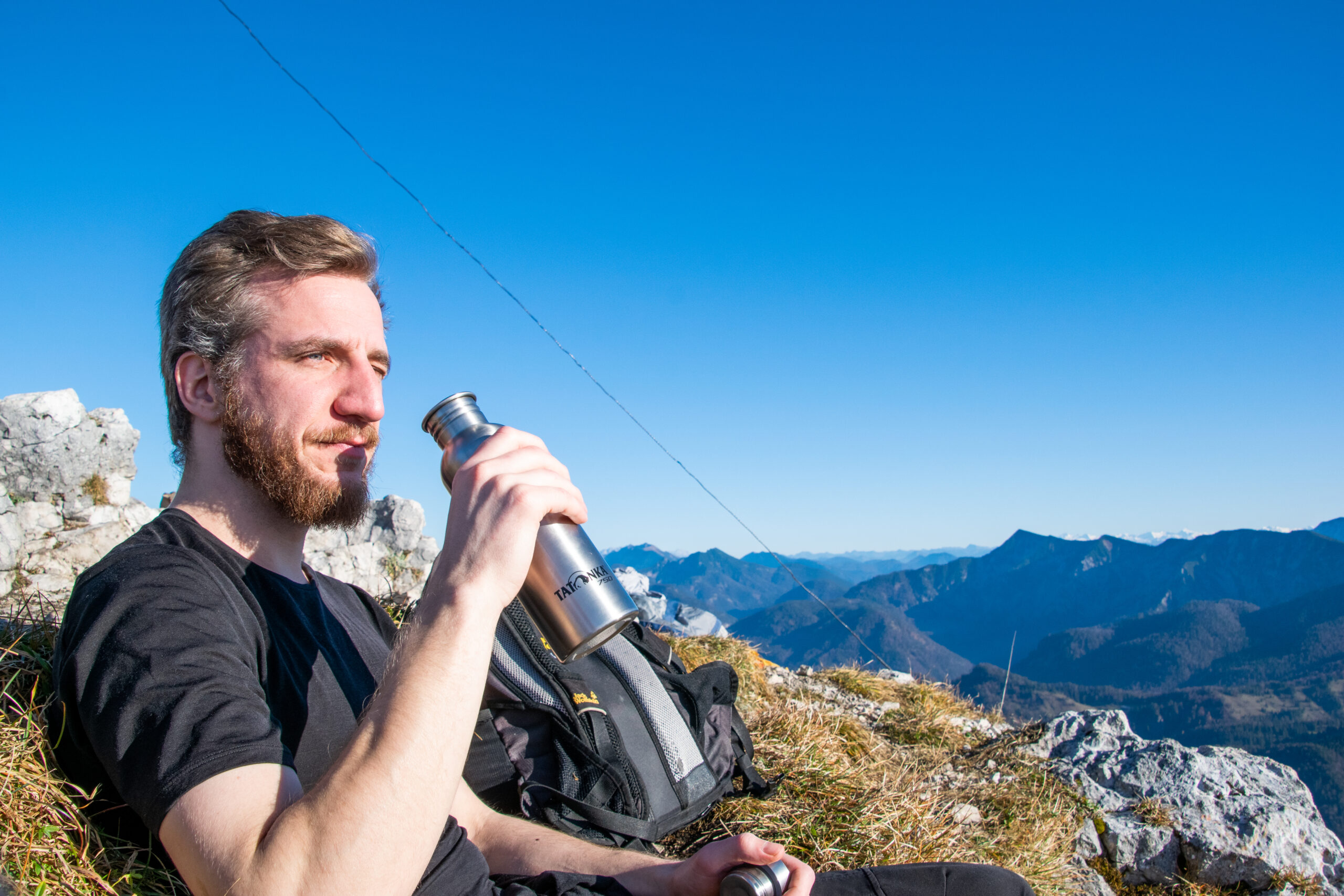 Person sitzt auf einem Berg und sieht in die Ferne - Ein Eindruck vom Emotionscoach, Begleiter, Unterstützer.